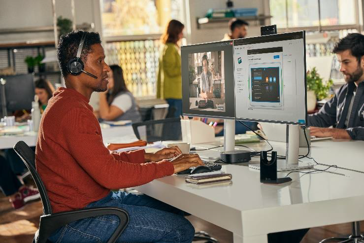 Example of an employee in front of monitors using Lens Pro for Rooms